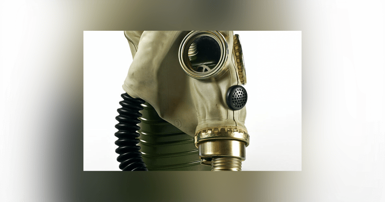 Vintage beige rubber gas mask with gold metal trim, black corrugated hose, and perforated filter cartridge against a plain white background