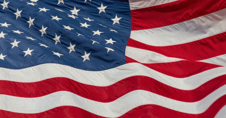 A close-up of the American flag waving in the wind, showing its blue field with white stars and red and white stripes