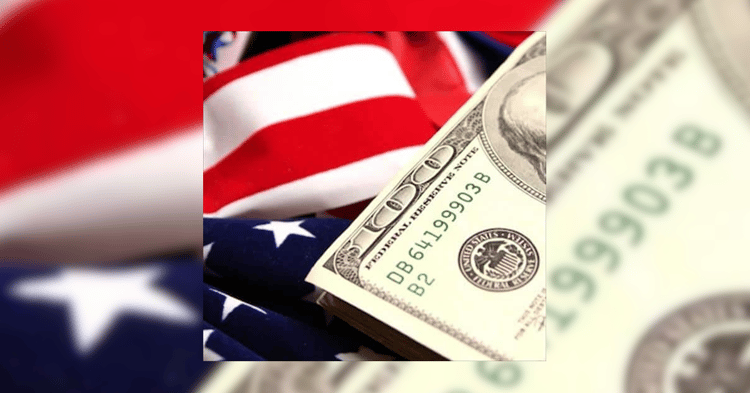 US dollar bills, including a visible hundred-dollar bill with the Federal Reserve seal and serial number, resting on a folded American flag