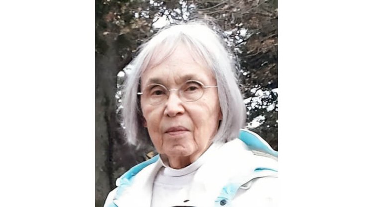 Fran Neumann, a Daphne artist known for her sculpture & advertising work, wearing glasses and a white jacket